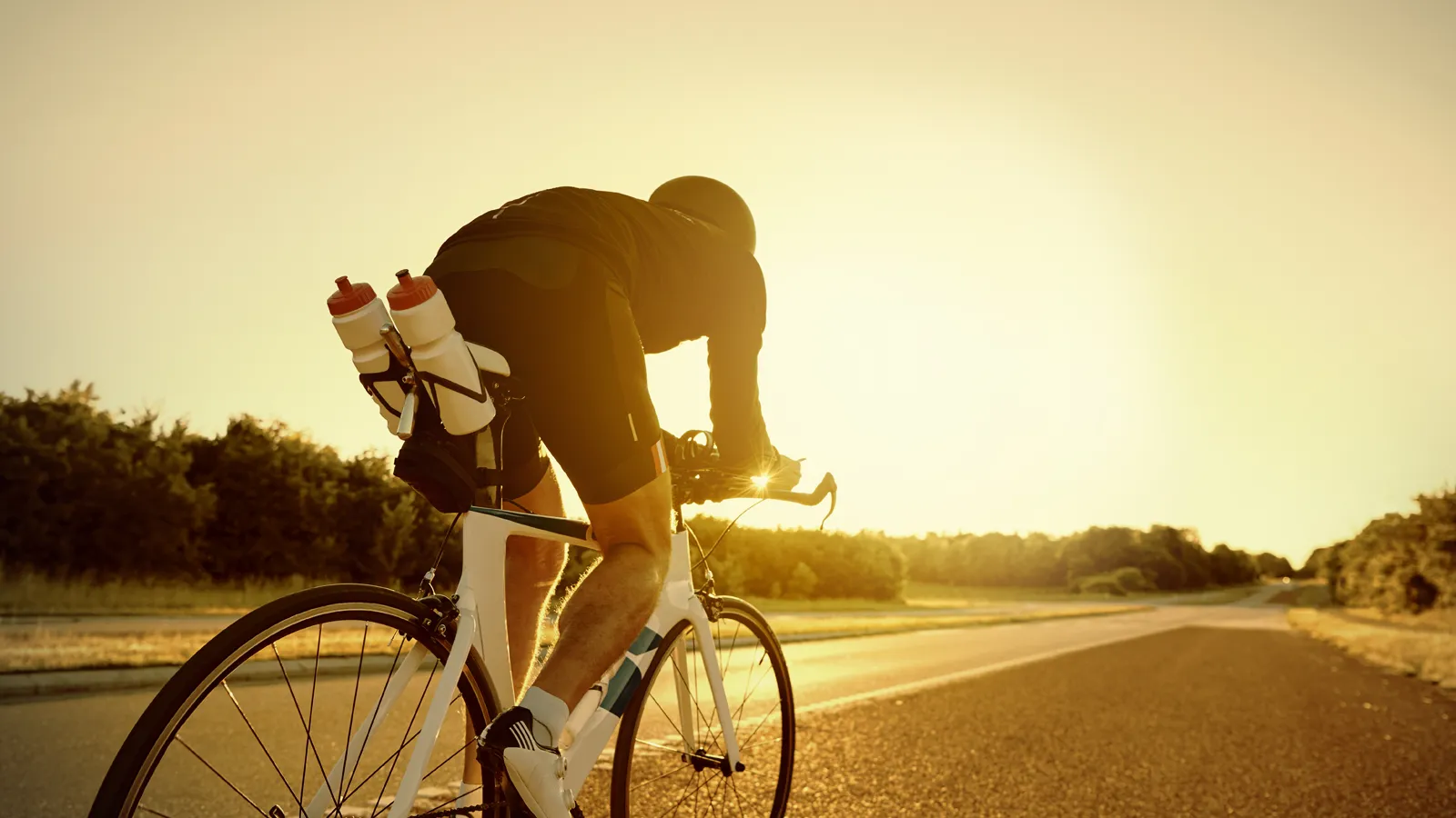 Cyclist pausing on an open road at sunrise
