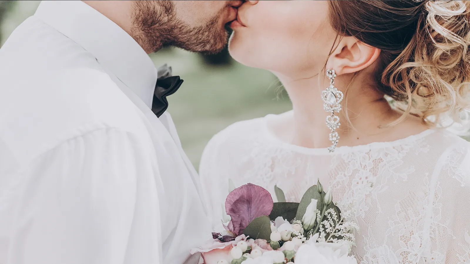 Newly married couple kissing outdoors after their wedding ceremony